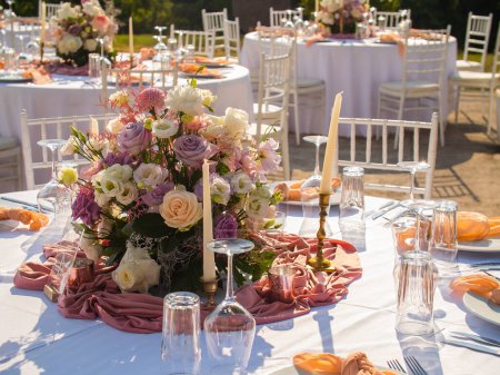 Foto de Boda. Banquete. Las sillas y la mesa redonda para los huéspedes, servidas con cubiertos, flores y vajilla y cubiertas con un mantel - Imagen libre de derechos