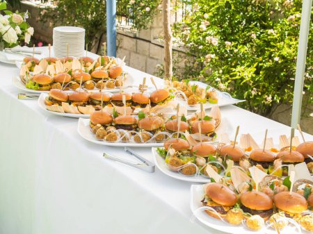 Photo for Banquet table with snacks food on plates hamburger party dinner table - Royalty Free Image