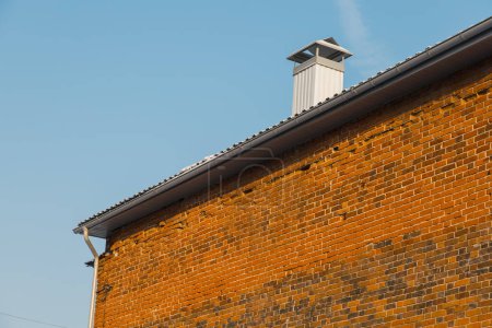 Foto de Cerca de la chimenea en el techo y el cielo, pared de ladrillo de la casa - Imagen libre de derechos
