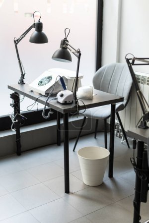 Mesa moderna con clavos paleta de colores y lámpara situada en el salón. Lugar de trabajo para la manicura. Interior