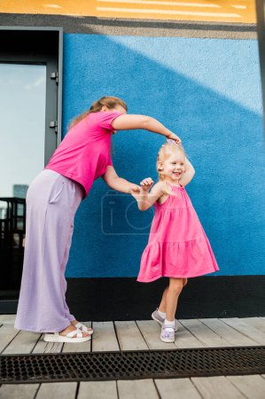 Photo for Blonde little girl with cochlear implant playing with her mother outdoor. Hear impairment deaf and health concept. Diversity and inclusion. Copy space. - Royalty Free Image