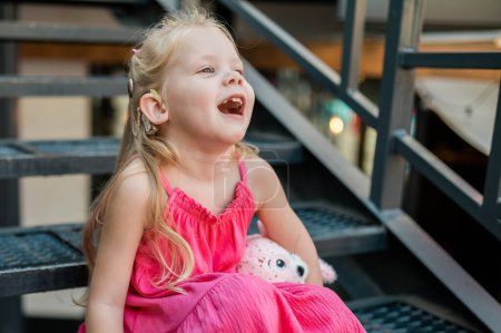 Mädchen mit Hörgeräten und Cochlea-Implantaten haben Spaß beim Sprechen und Spielen im Freien. Kopierraum und leerer Platz für Werbung.