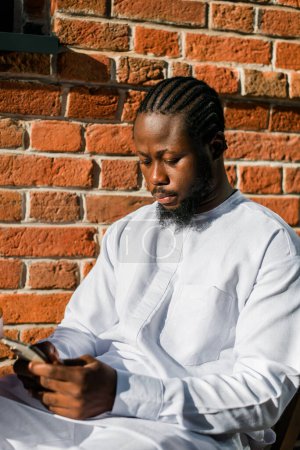 Téléchargez les photos : Millénaire génération homme afro-américain dactylographier sms extérieur 5g concept internet. Internet haut débit sur le téléphone et bavarder sur les réseaux sociaux et blog - en image libre de droit