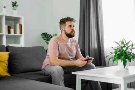 Man playing videogames in living room sitting on sofa