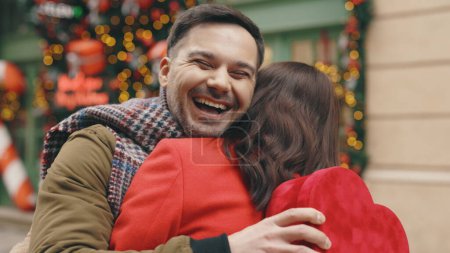 Foto de Happy couple in love. Valentines day. Romance, relationships. Husband gives his beautiful wife a red heart shape gift. Lovely couple in love spending time together exchanging presents.Festive mood - Imagen libre de derechos