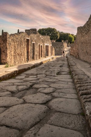 Téléchargez les photos : Pompéi, Italie-27 avril 2024 : Promenade dans le temps : Rues en pierre de Pompéi depuis le niveau du sol, baignées de lumière de l'après-midi sous un ciel couchant, Vue grand angle sur les ruines. - en image libre de droit