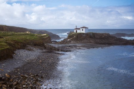 Photo for Atlantic Ocean Coastline. Galicia, Spain. Scenic view of a white chapel on top of a rock and a rolling stone beach. A Virxe do Porto Ermitage - Royalty Free Image