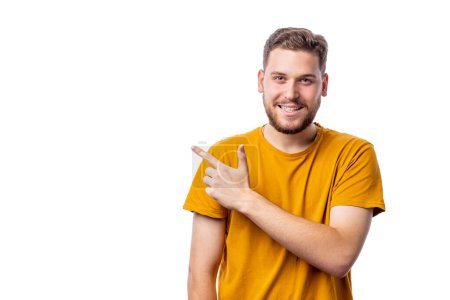 Happy bearded man in bright yellow pointing at copy space with finger isolated over white background