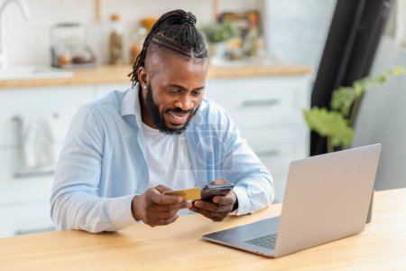 Photo for African american man doing online shopping at home using laptop computer and credit card, online banking, ordering goods via internet concept - Royalty Free Image