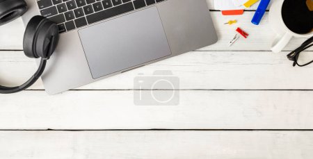 Photo for Online learning, working or workplace concept. Laptop, headphones, coffee cup, eyeglasses and office supplies on white wooden table with copy space top view - Royalty Free Image