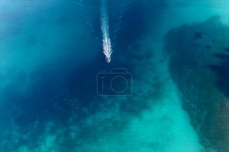 Photo for Top view from drone of fast sailing yacht, speed boat cruising in high speed in clear blue water in the ocean or sea in summer. Aerial view. Summer vacation, weekend at sea, travel background - Royalty Free Image