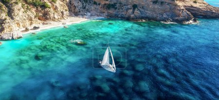 Photo for Travel, hobby concept. Beautiful seascape with white sailing yacht off the coast with sandy beach in summer on a sunny day aerial view - Royalty Free Image