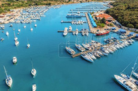 Photo for Aerial view of luxure yachts and motorboats moored in a port with clear blue water in summer. Top view from drone of sailboats and various speed boats in dock. Pula, Croatia - Royalty Free Image