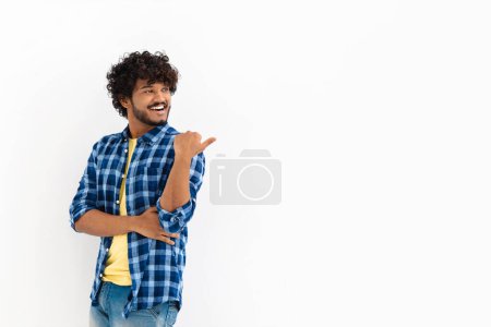 Photo for Young Asian man with curly hair and casual stylish clothes smiling with his finger pointing on a white background with copy space, smiles friendly - Royalty Free Image