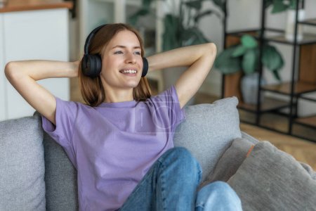 Photo for Relax at home, positive thinking. Portrait of happy young caucasian woman in headphones listening to her favorite music thinking of something good, looking away and smiles friendly - Royalty Free Image