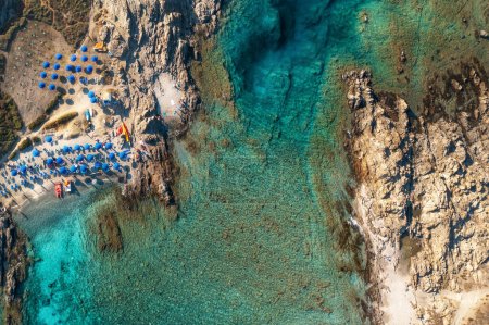 Photo for Top view of beautiful sandy beach with turquoise sea water and colorful blue umbrellas on the Sunset, Islands of Sardinia in Italy, aerial drone shot - Royalty Free Image