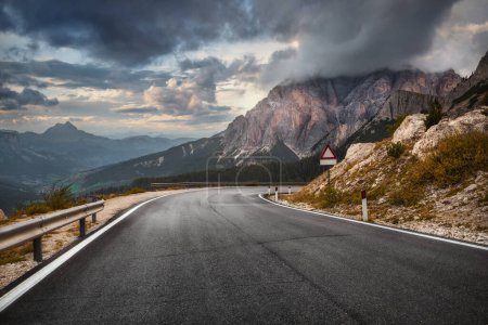 Téléchargez les photos : Autoroute en montagne en soirée d'automne en Italie. Beau paysage avec route. Route asphaltée vide sur fond de belle roche. Dolomites, Alpes - en image libre de droit