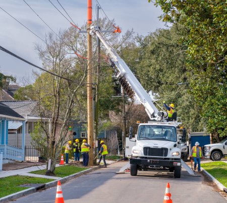 Téléchargez les photos : NEW ORLEANS, LA, USA - JANUARY 20, 2023: Workers and truck with attached crane replacing a utility pole in a residential neighborhood - en image libre de droit