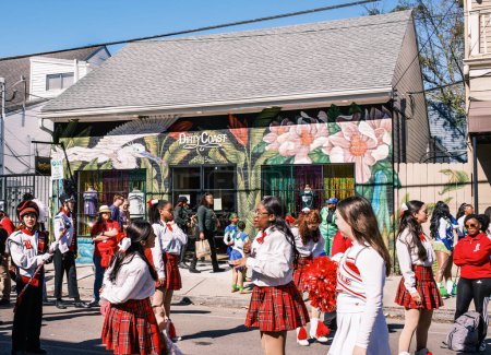 Téléchargez les photos : NEW ORLEANS, LA, USA - FEBRUARY 12, 2023: Young women from Riverdale High School gathered to march in Mardi Gras Parade in front of the Dirty Coast gift shop on Magazine Street - en image libre de droit