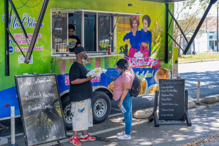 Foto de NEW ORLEANS, LA, Estados Unidos - 5 de marzo de 2023: Clientes y trabajadores de Tisha 's So Damn Good food truck en Elysian Fields Avenue - Imagen libre de derechos