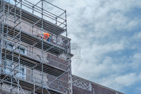 Photo for NEW ORLEANS, LA, USA - AUGUST 16, 2023: Worker on a scaffold renovating the facade of Willow High School - Royalty Free Image