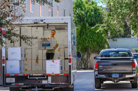 Téléchargez les photos : NOUVELLE-ORLÉANS, LA, ÉTATS-UNIS - 17 AOÛT 2023 : Un homme soulève une boîte à l'arrière d'un camion chargé lors d'un déménagement dans un immeuble d'habitation dans le centre-ville de la Nouvelle-Orléans - en image libre de droit