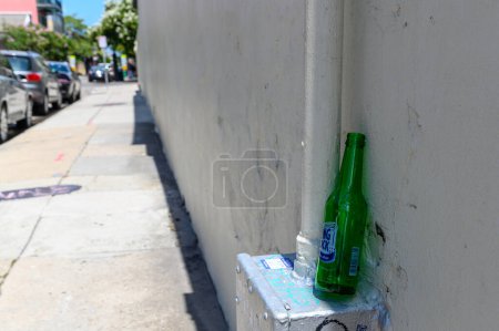 Téléchargez les photos : NEW ORLEANS, LA, USA - 6 AOÛT 2023 : Mise au point sélective sur une bouteille de bière Rolling Rock jetée reposant contre le mur du vieux couvent des Ursulines dans le quartier français - en image libre de droit