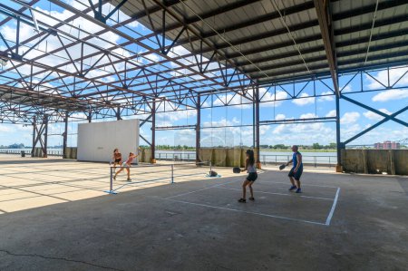 Téléchargez les photos : NEW ORLEANS, LA, ÉTATS-UNIS - 6 AOÛT 2023 : Des gens jouent au pickle ball au parc Crescent avec le fleuve Mississippi en arrière-plan - en image libre de droit