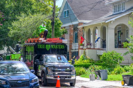 Photo for NEW ORLEANS, LA, USA - AUGUST 10, 2023: Workers atop Tree Masters tree service truck stow away equipment at the end of a work day in an Uptown neighborhood - Royalty Free Image