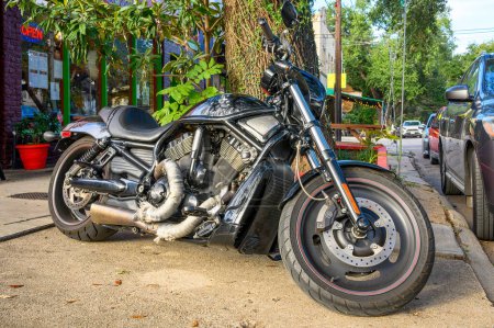 Photo for NEW ORLEANS, LA, USA - SEPTEMBER 28, 2023: Shiny black Harley-Davidson motorcycle, displaying some wear and tear parked in front of the sidewalk on S. Carrollton Avenue - Royalty Free Image