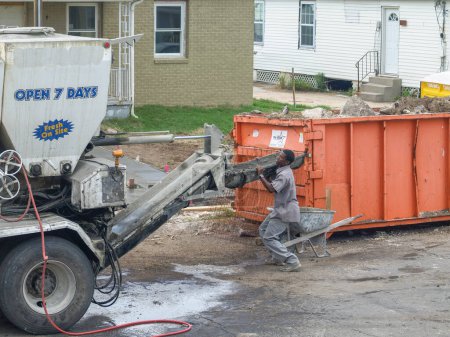 Téléchargez les photos : NEW ORLEANS, LA - 20 JUIN 2008 : Travailleur du ciment avec camion de ciment et benne à ordures sur la chaussée dans le quartier de Gentilly - en image libre de droit
