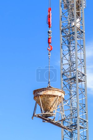 Crane lifts a portable cement mixer at a construction site