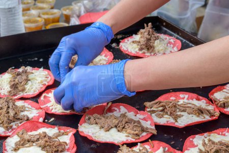 Manos con guantes preparan tacos de cerdo en el Freret Street Festival en Nueva Orleans, Luisiana, EE.UU.