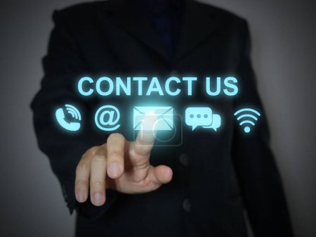 Photo for Contact us or Customer support concept. Businessman tapping on a virtual screen of contact icons:  phone, address, email, live chat, and internet wifi - Royalty Free Image
