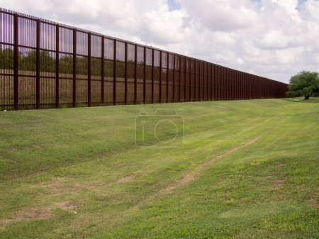 Photo for Standing tall and imposing, the rusty steel fence on the USA-Mexico border in Laredo, Texas serves as a visual reminder of the complex relationship between the two neighboring countries. The fence, which stretches for many miles in either direction, - Royalty Free Image