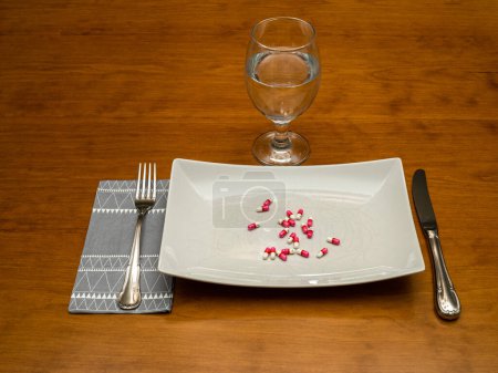 Photo for Allergy pills on white plate with glass of water, fork and knife - Royalty Free Image