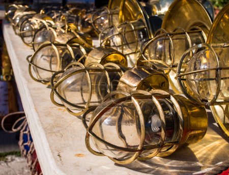 Photo for Rows of vintage brass lamps on display at a local flea market, showcasing the beauty and history of these unique lighting fixtures. These lamps, with their ornate designs and aged patina, are a testament to the artistry and craftsmanship of a bygone - Royalty Free Image