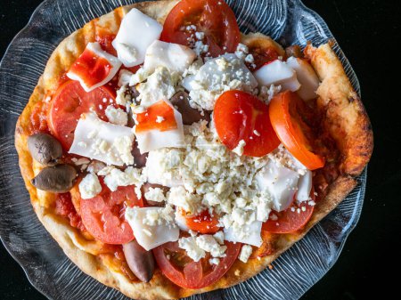 Photo for This delicious home made pizza is fairly healthy. It's made of naan bread, tomatoes, black calamata (kalamata) olives, crab sticks and feta cheese. Here it's served on a glass plate. - Royalty Free Image