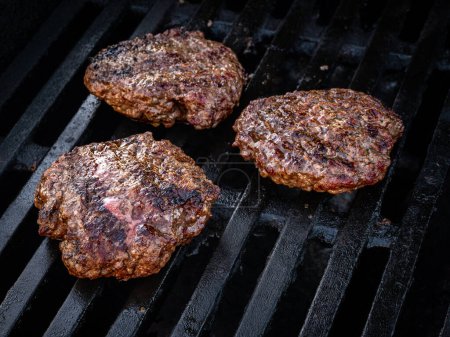 Photo for The classic simplicity of three plain burgers, cooked to perfection on a grill for a summer cookout. The beef patties are juicy and flavorful, with no toppings to distract from their deliciousness. Perfect for a fast food fix or as the main meal at a - Royalty Free Image