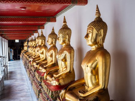 Photo for A stunning sight of a long line of Golden Buddha statues adorning the wall of Wat Pho Temple in Bangkok, Thailand. The intricate designs and shimmering gold surface of the statues create a sense of awe and wonder, inviting visitors to contemplate and - Royalty Free Image
