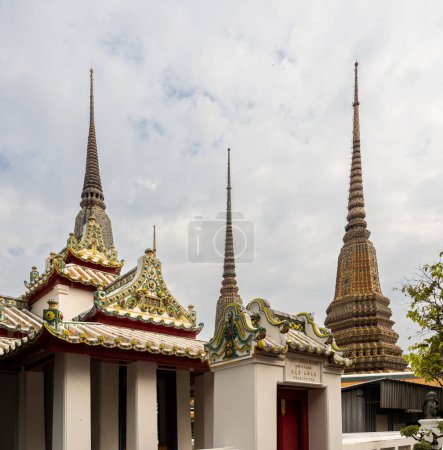 Photo for The sky is the backdrop for the golden towers and some of the building of the Wat Pho temple in Bangkok, Thailand. - Royalty Free Image