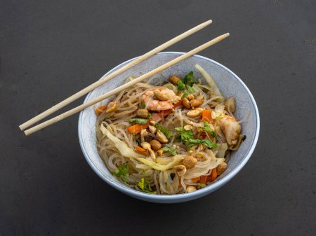 Photo for Fresh shrimps, flavorful noodles, nutritious vegetables, and crunchy peanuts served in an elegant white bowl with chopsticks. - Royalty Free Image