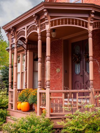 Photo for In Stowe, Vermont, USA, a vibrant, red porch comes alive with the vivid hues of pumpkins and mums flowers, creating a colorful and enchanting scene. - Royalty Free Image