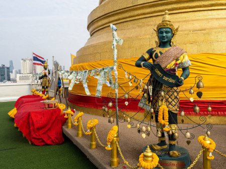 Photo for Captured up close, a statue rests beneath the temple's gilded spire atop Wat Saket, the Golden Mount, in Bangkok, Thailand. - Royalty Free Image