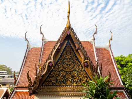 Photo for Exquisite intricacies adorn a red roof embellished with golden details, gracing a house within Bangkok's Wat Saket, also known as the Golden Mount temple in Thailand. - Royalty Free Image