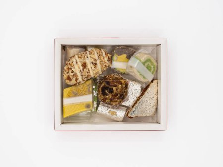 Foto de Vista superior de una caja llena de surtidos y deliciosos dulces de ghee indios, aislados sobre un fondo blanco. - Imagen libre de derechos