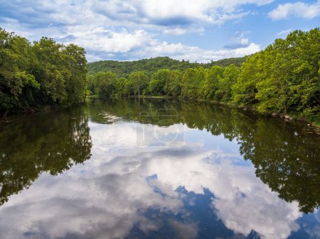 Das ruhige Wasser des South Fork des Shenandoah River in Virginia, USA, spiegelt die umliegenden Bäume, den Himmel und Wolken wider.