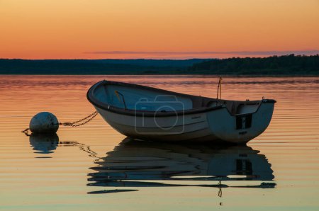 Téléchargez les photos : Un coucher de soleil à couper le souffle et vif peint le ciel au-dessus du lac Finjasjon, juste à l'extérieur d'Hassleholm, en Suède. Les eaux sereines reflètent deux bateaux et leurs reflets captivants. - en image libre de droit