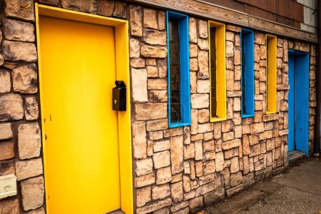 Téléchargez les photos : Une charmante maison en pierre aux portes et fenêtres bleues et jaunes frappantes, évoquant les teintes vibrantes des drapeaux de Suède et d'Ukraine. - en image libre de droit