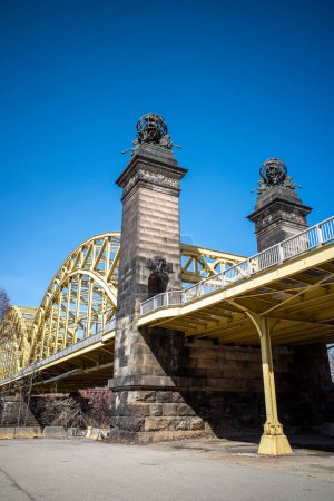 Soaring steel of the Sixteenth Street Bridge, Pittsburgh, Strip District, framed by clear blue sky.